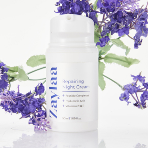 Image of a white bottle labeled 'Repairing Night Cream' next to purple flowers on a white background